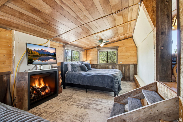 1663 Lancer Lane Evanston, UT 82930 - Photo 20 of 101 Wood-paneled walls and ceiling with an angled roofline, featuring an electric fireplace and ceiling fan