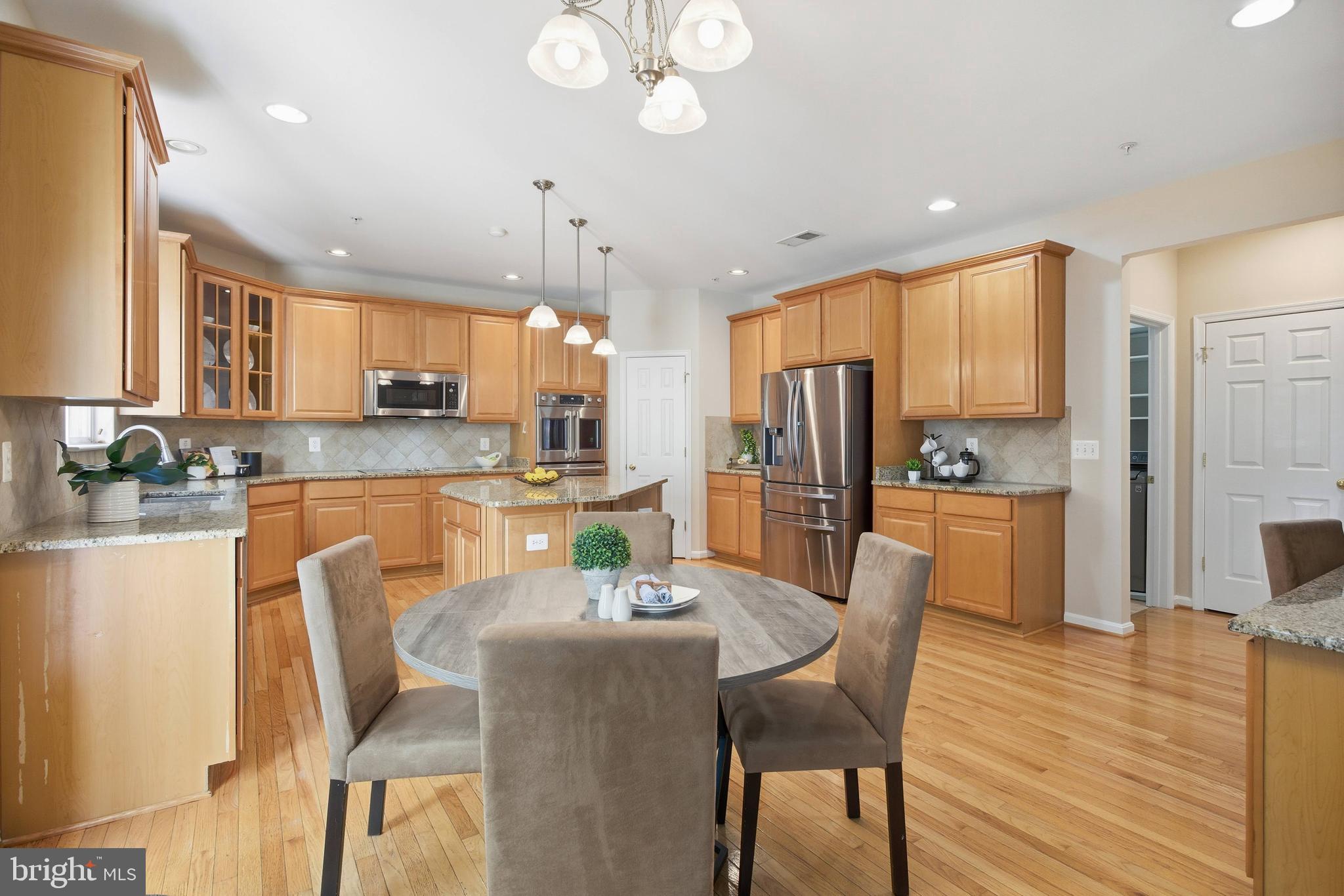 9013 Helmsley Drive Clinton, MD 20735 - Photo 5 of 68 a kitchen with stainless steel appliances kitchen island granite countertop a refrigerator a stove top oven a sink dishwasher and white cabinets with wooden floor