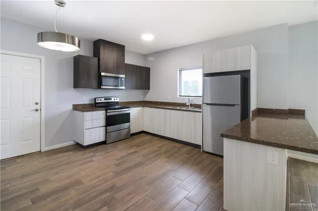 a kitchen with stainless steel appliances granite countertop a refrigerator a stove a sink and a microwave