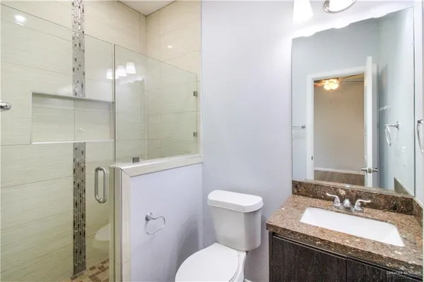 a bathroom with a granite countertop sink toilet a mirror and shower