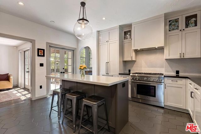 a kitchen with stainless steel appliances granite countertop a stove a sink dishwasher a refrigerator and a dining table with wooden floor