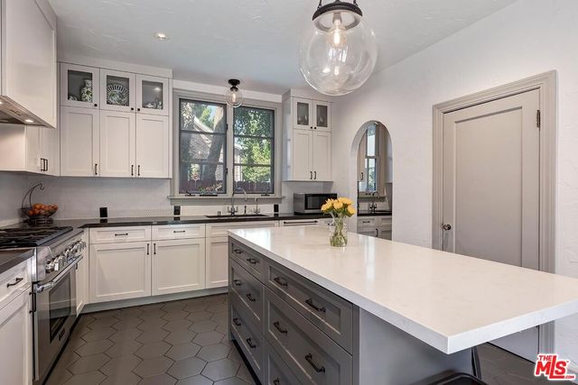 a kitchen with a sink dishwasher a stove and white cabinets with wooden floor