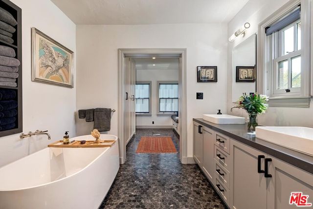 a bathroom with a granite countertop tub sink and mirror
