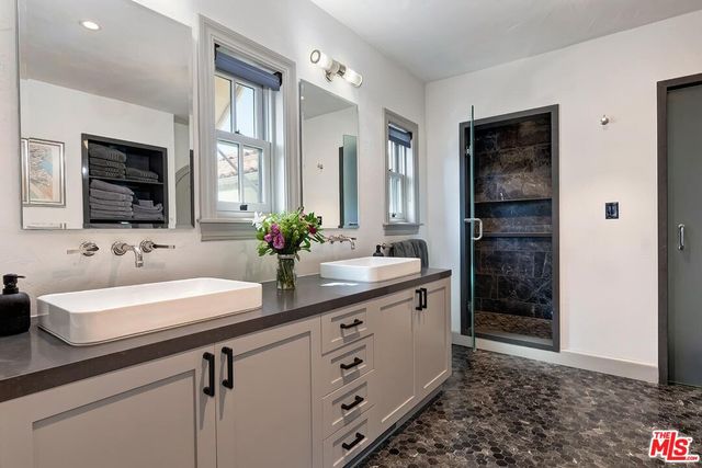 a bathroom with a double vanity sink a mirror and a shower