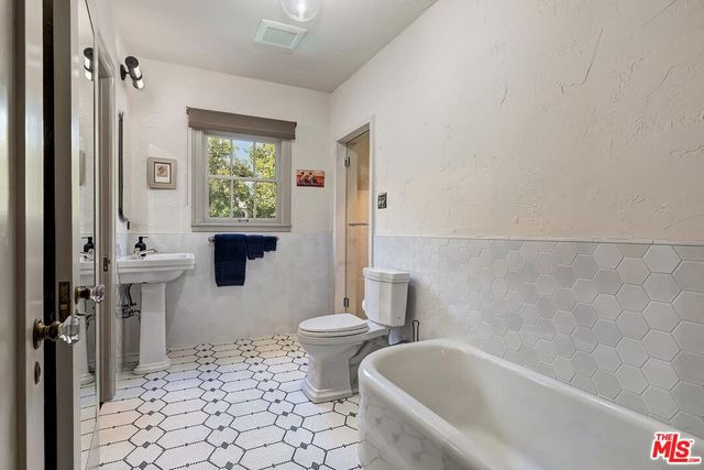 a bath room with a toilet a bath tub and a shower