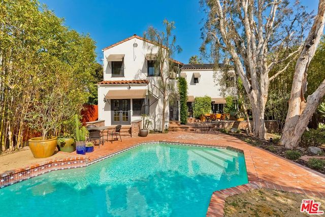 a view of a patio with table and chairs potted plants and large tree