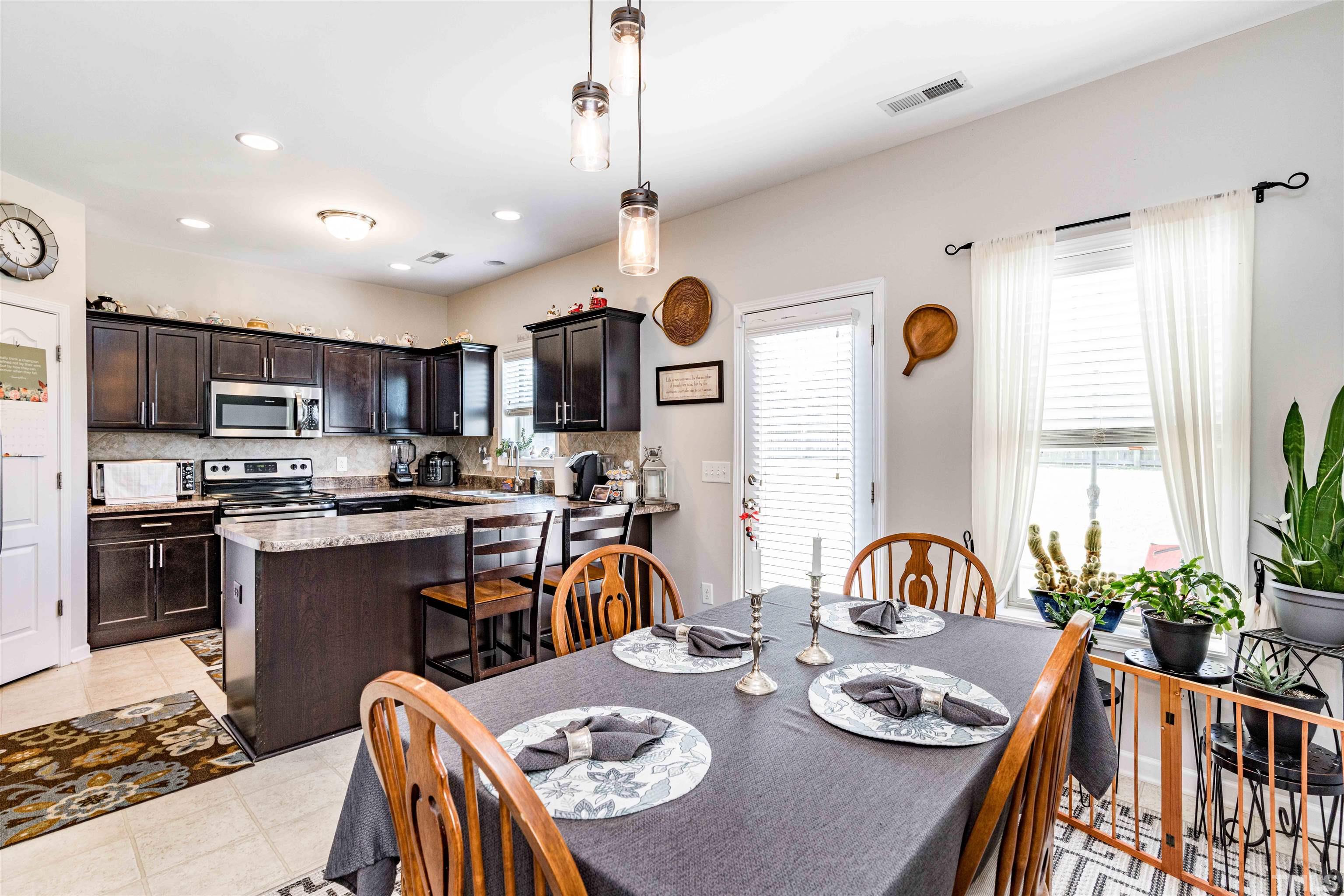 180 Crane Way Bunnlevel, NC 28323 - Photo 17 of 26 a kitchen with stainless steel appliances granite countertop a stove a kitchen island a refrigerator a stove a dining table and chairs with wooden floor
