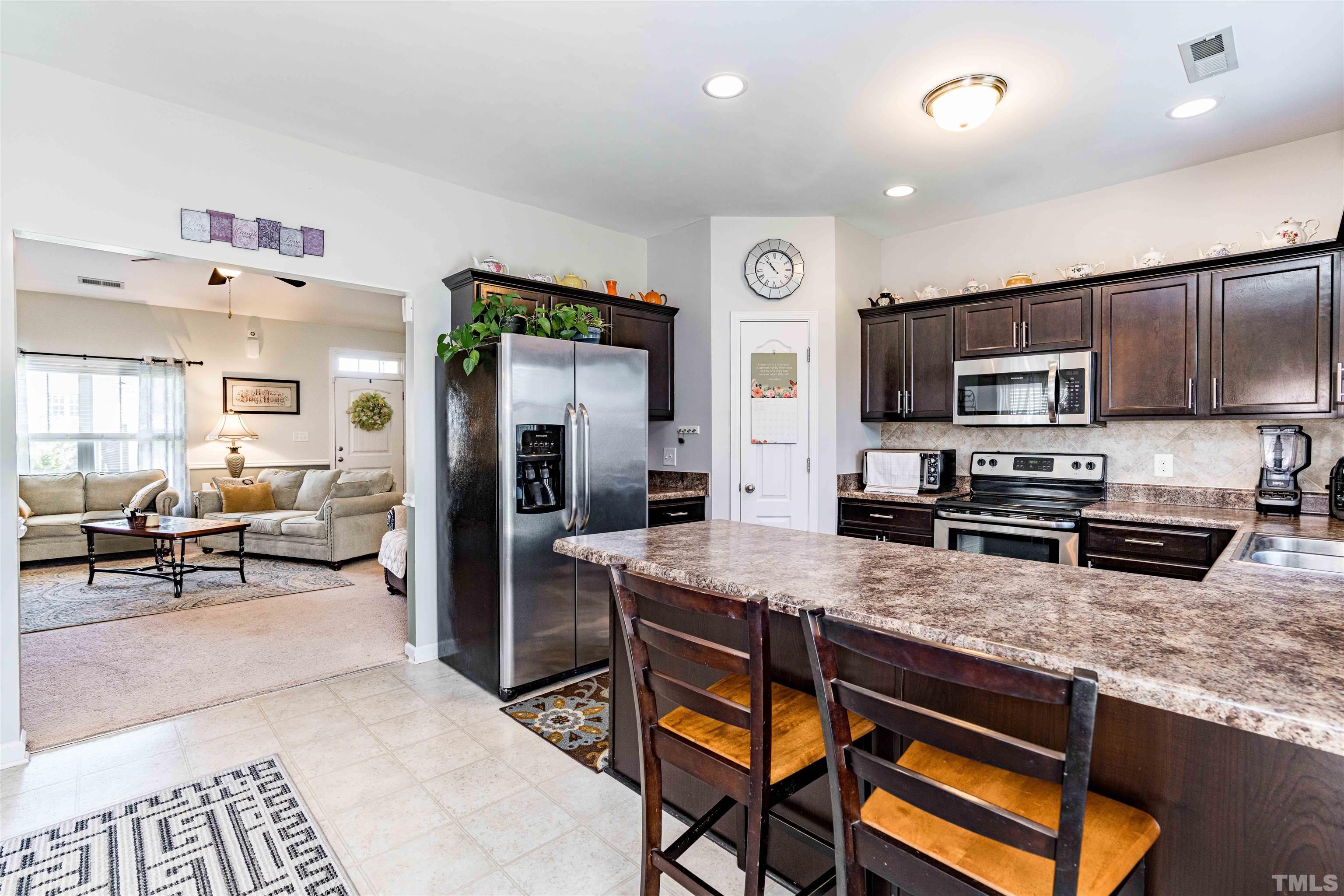 180 Crane Way Bunnlevel, NC 28323 - Photo 18 of 26 a kitchen with stainless steel appliances granite countertop a stove top oven a sink dishwasher a dining table and chairs with wooden floor