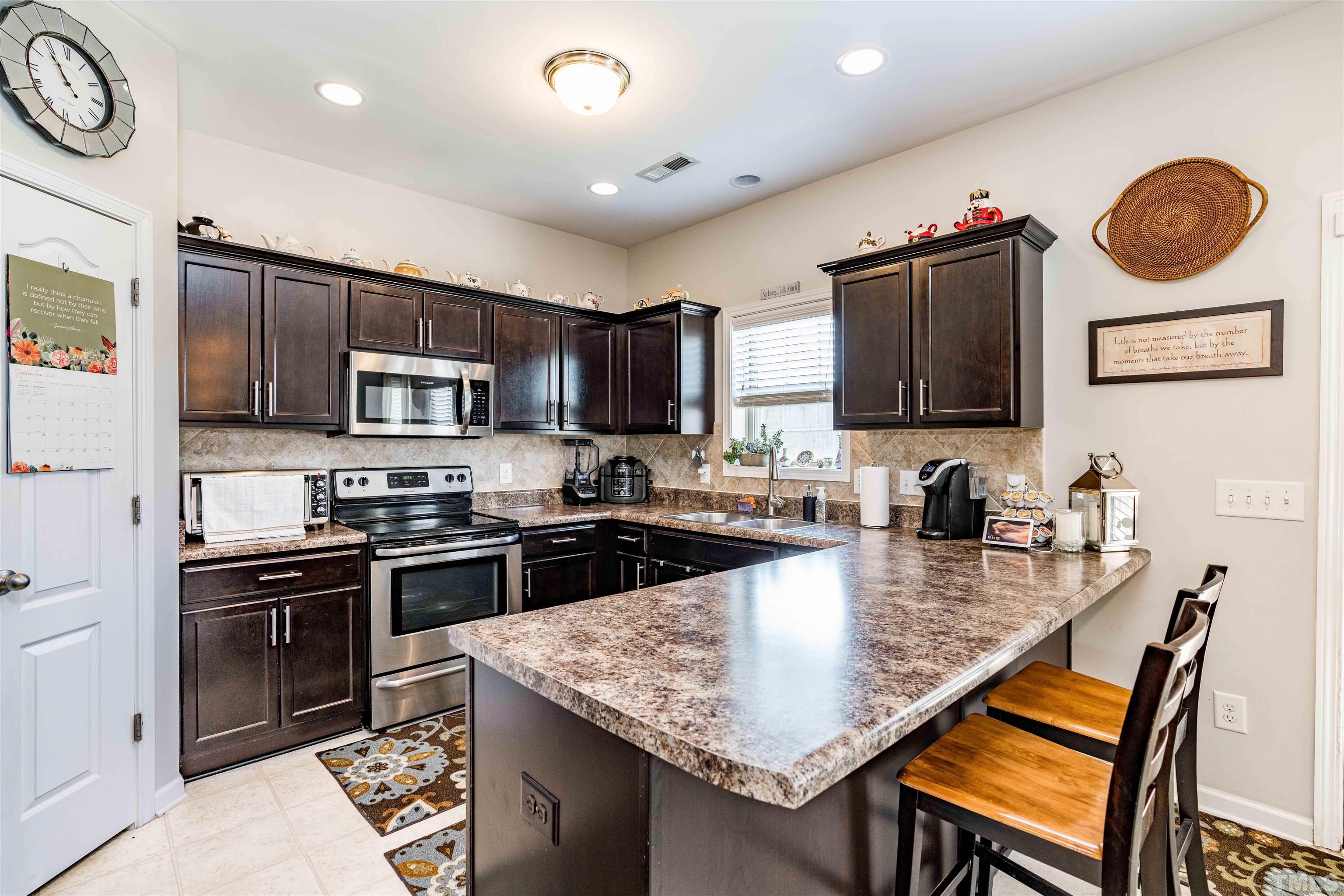 180 Crane Way Bunnlevel, NC 28323 - Photo 19 of 26 a kitchen with stainless steel appliances granite countertop a stove top oven a sink dishwasher a dining table and chairs with wooden floor