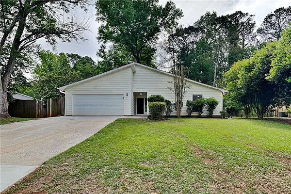 a view of a house with a yard and large trees