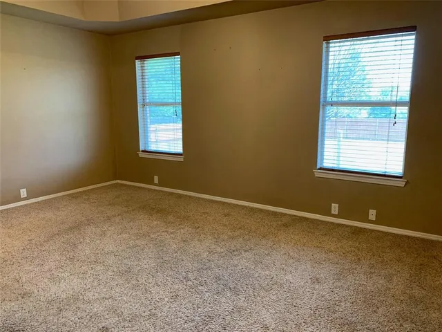 an empty room with a chandelier fan and windows