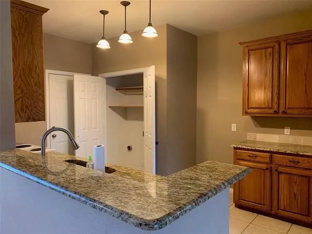 a kitchen with kitchen island granite countertop a sink cabinets and stainless steel appliances