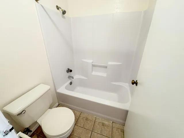 a white toilet sitting next to a bath tub