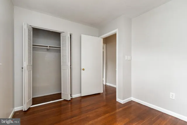a view of an empty room with wooden floor and closet