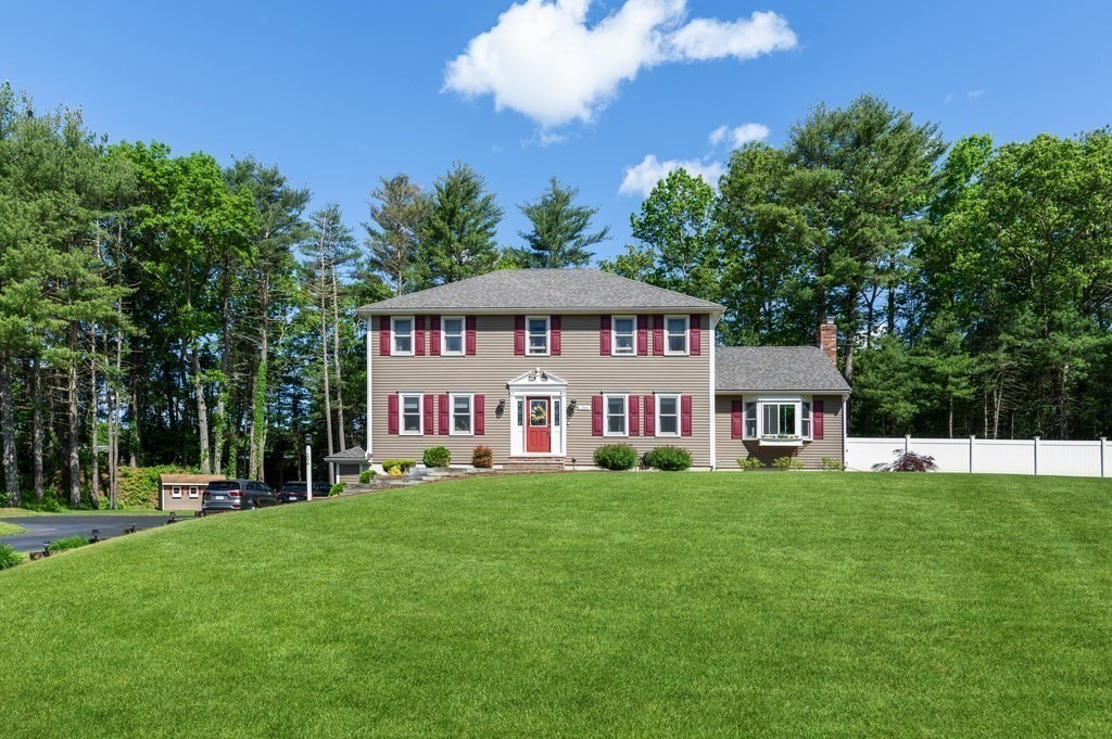 a white house with a big yard and large trees