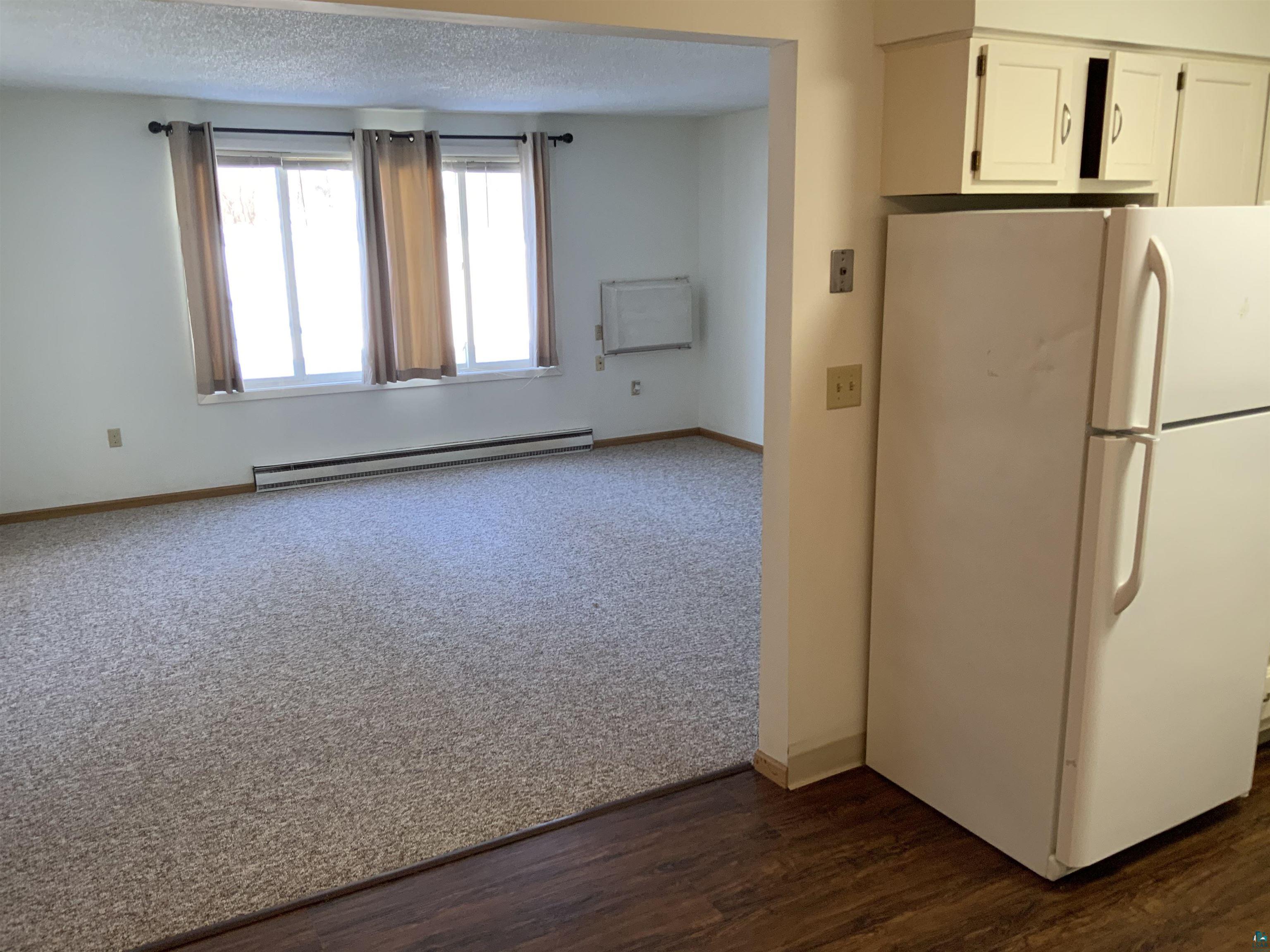 850 Spring Lake Road Cloquet, MN 55720 - Photo 13 of 18 Kitchen featuring white fridge, white cabinetry, dark hardwood / wood-style flooring, a baseboard radiator, and a textured ceiling