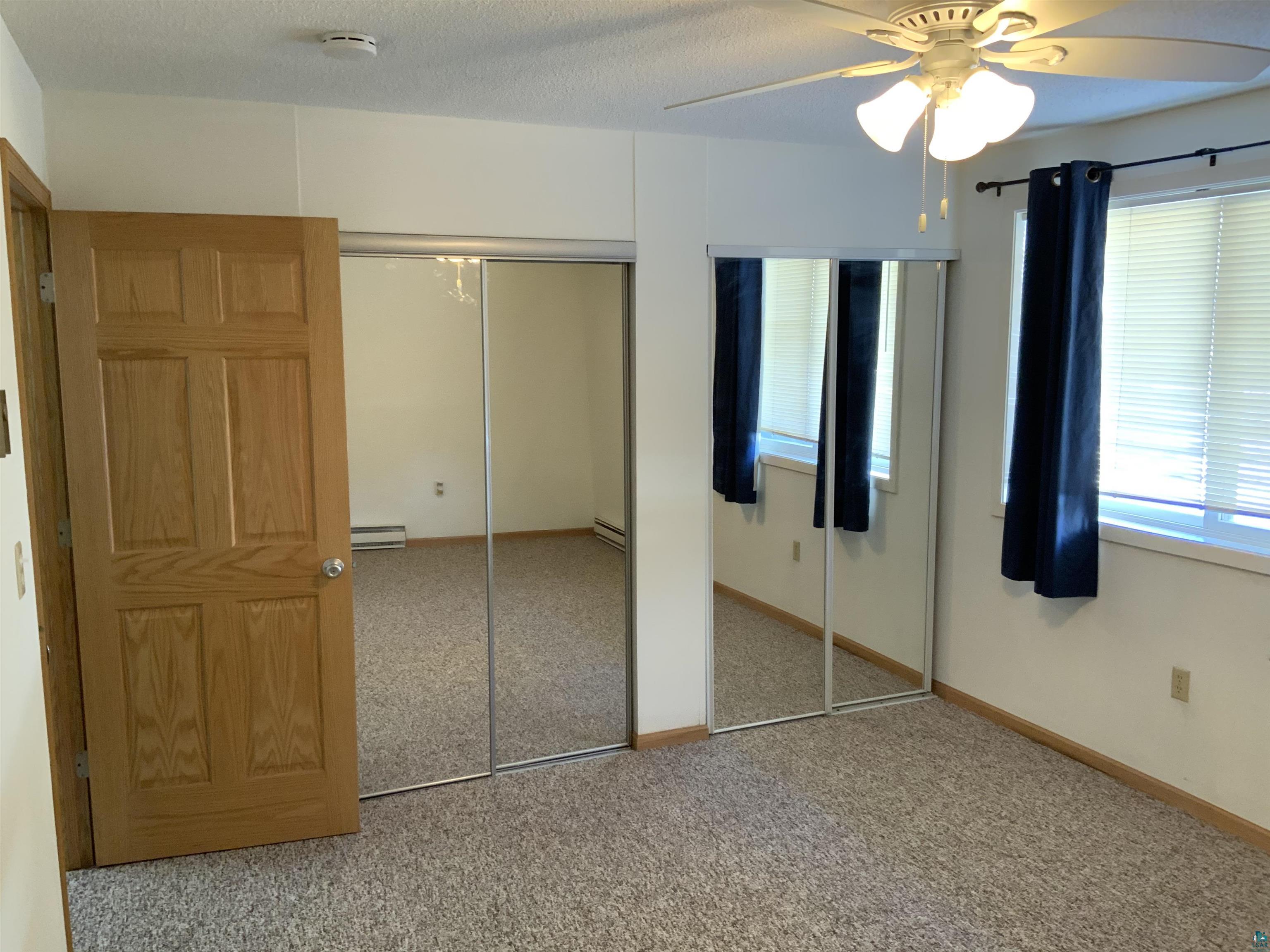 850 Spring Lake Road Cloquet, MN 55720 - Photo 16 of 18 Unfurnished bedroom featuring multiple windows, a baseboard radiator, carpet floors, and ceiling fan