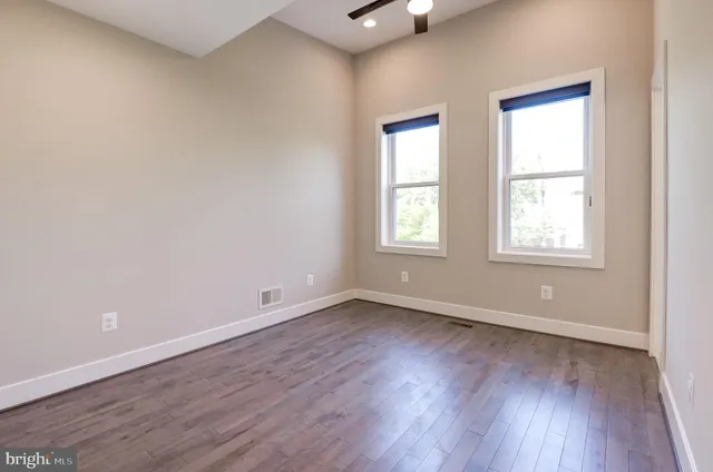 an empty room with wooden floor and windows