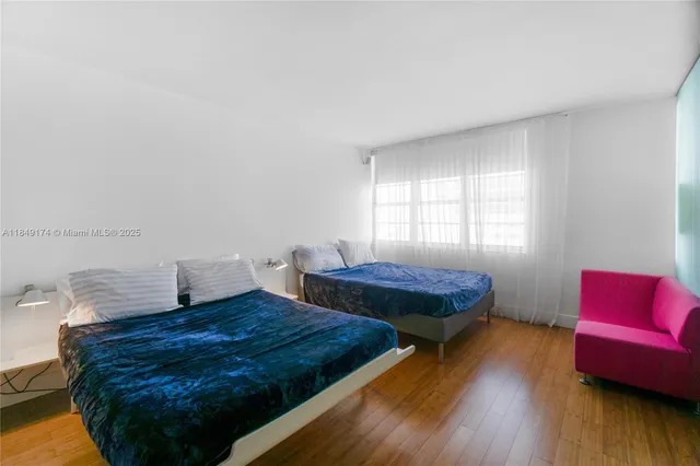 a bedroom with two beds and wooden floor
