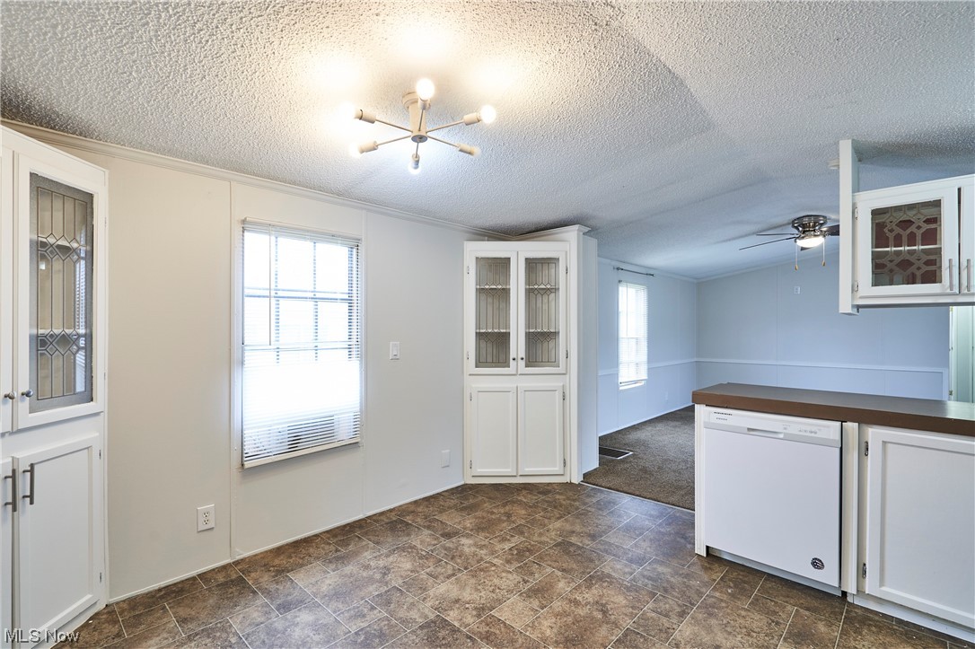 45 Eddie Road Madison, OH 44057 - Photo 9 of 26 Empty room featuring dark tile floors, ceiling fan with notable chandelier, lofted ceiling, and a textured ceiling