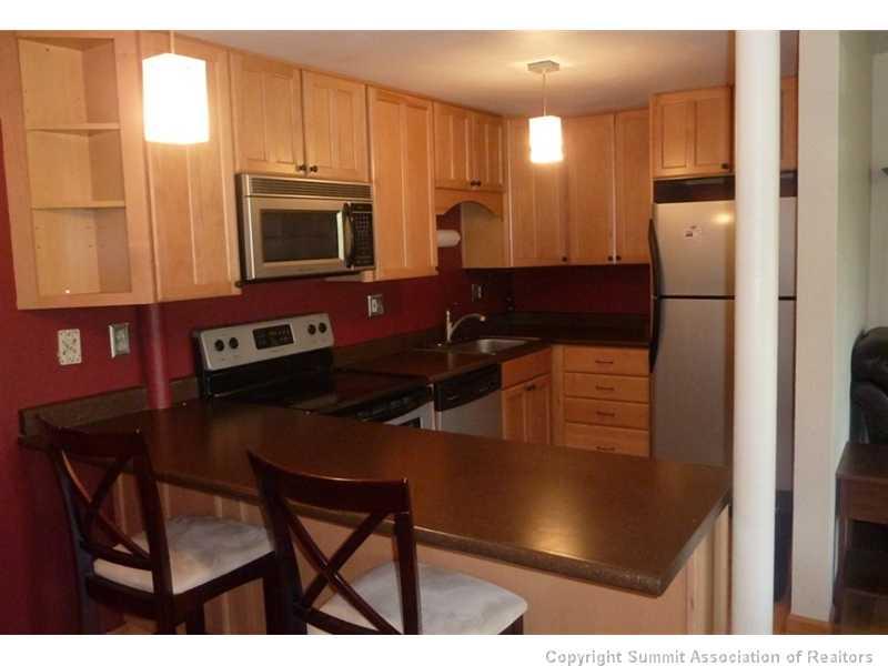110 Evergreen Road, Unit 104B Dillon, CO 80435 - Photo 14 of 19 a kitchen with a table chairs refrigerator and microwave