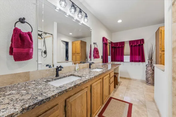 a bathroom with a granite countertop double vanity sink and shower