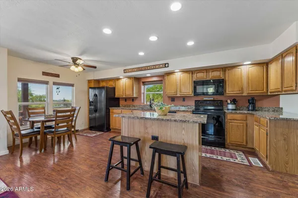 a kitchen with stainless steel appliances kitchen island granite countertop a stove top oven a sink a dining table and chairs with wooden floor