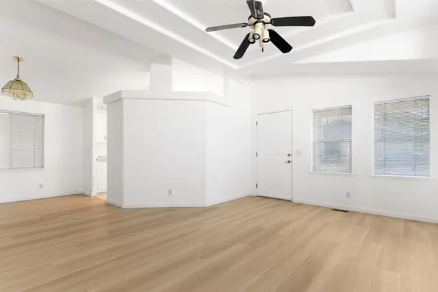 a view of an empty room with wooden floor and windows
