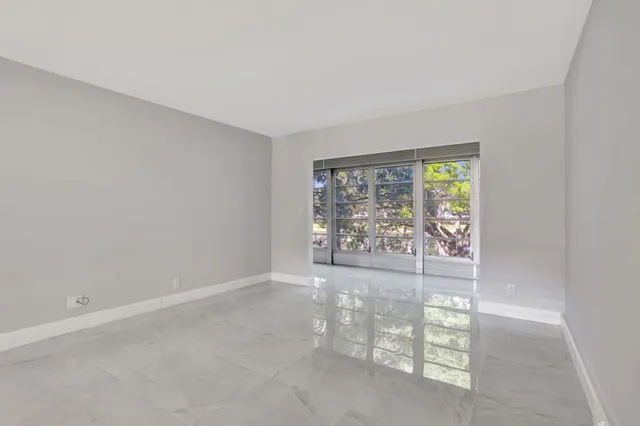 an empty room with floor to ceiling window and an outdoor view