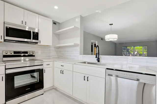 a kitchen with granite countertop white cabinets white stainless steel appliances and a sink