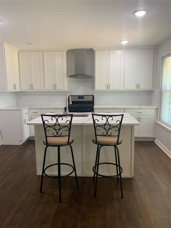 a kitchen with stainless steel appliances a table chairs in it and wooden floors