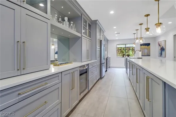 a large white kitchen with a large kitchen island a stove a sink a chimney and a refrigerator