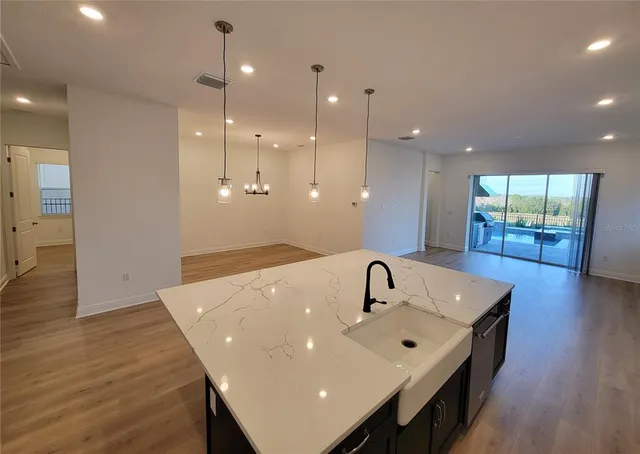 a bathroom with a sink a large mirror and wooden floor