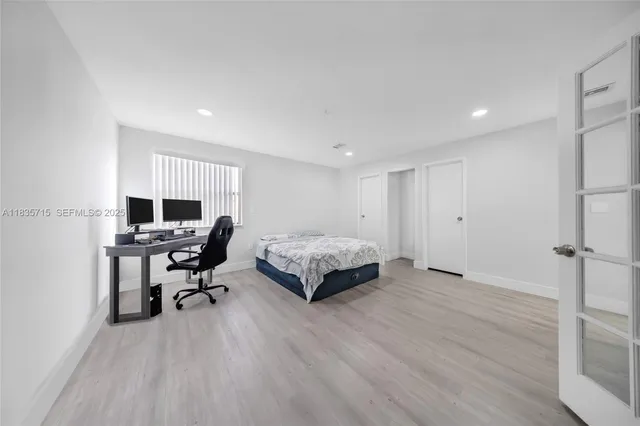 a spacious bedroom with a bed and wooden floor