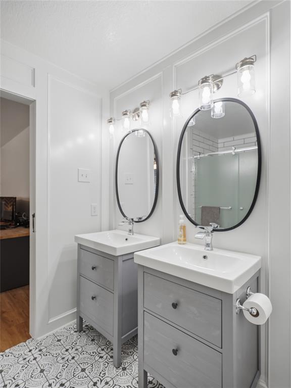 12724 Carpenter Lane Rhome, TX 76078 - Photo 17 of 37 Dual vanity bathroom featuring patterned floor tiling, white board and batten wall detailing, and brushed nickel light fixtures