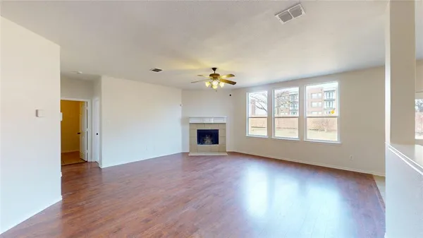 an empty room with wooden floor fireplace and windows