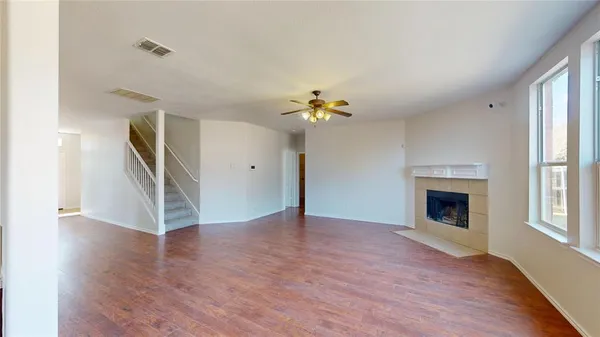 a view of an empty room with wooden floor fireplace and a window