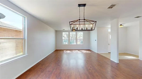 a view of empty room with wooden floor and window