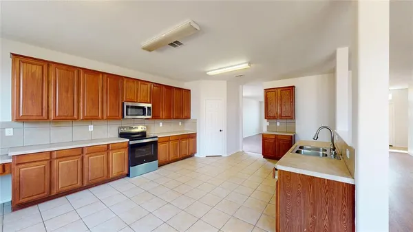 a kitchen with stainless steel appliances a stove top oven a sink dishwasher and a refrigerator
