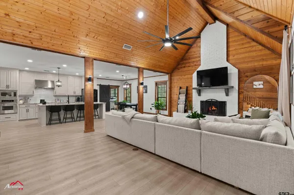 a living room with furniture a fireplace a flat screen tv and kitchen view