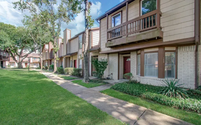 a view of brick building with a yard garden and large tree