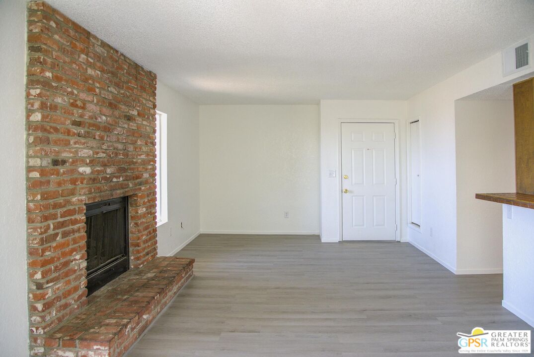 66565 12th Street, Unit 1 Desert Hot Springs, CA 92240 - Photo 1 of 10 a view of an empty room with wooden floor and a fireplace