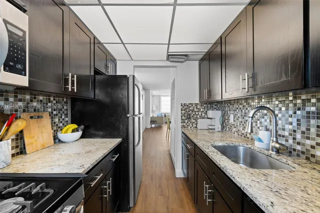 a kitchen with granite countertop a sink a counter space appliances and cabinets