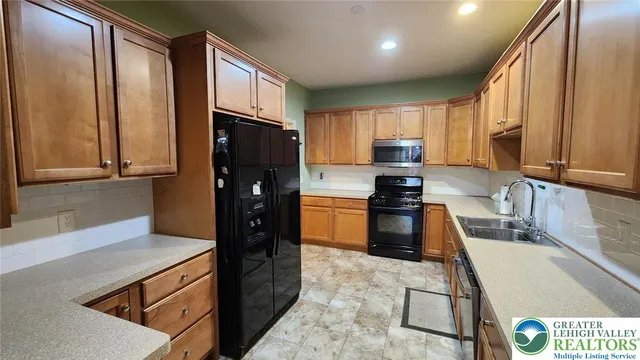 a kitchen with granite countertop a refrigerator a stove top oven and a sink