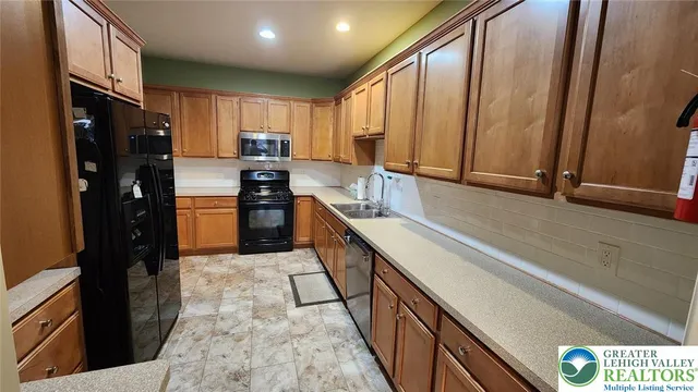 a kitchen with stainless steel appliances granite countertop a refrigerator a stove and a sink with wooden floor