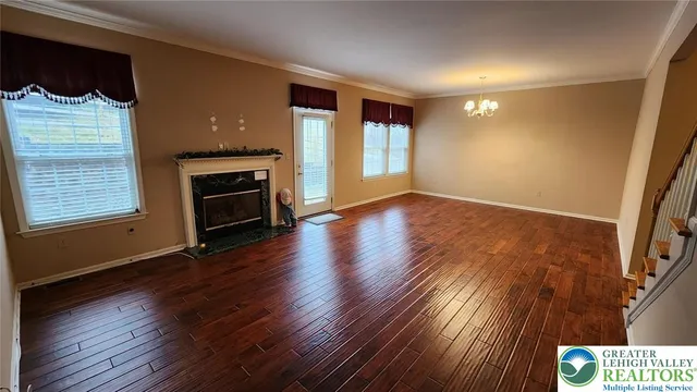 an empty room with wooden floor fireplace and windows