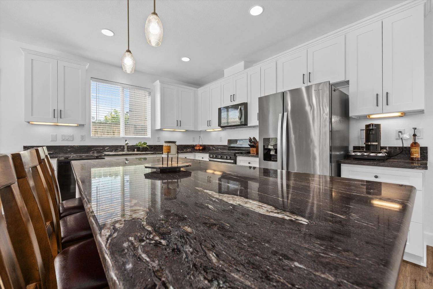 5407 Mensen Drive Bakersfield, CA 93313 - Photo 12 of 36 a kitchen with stainless steel appliances granite countertop a refrigerator a stove a sink a stove and white cabinets