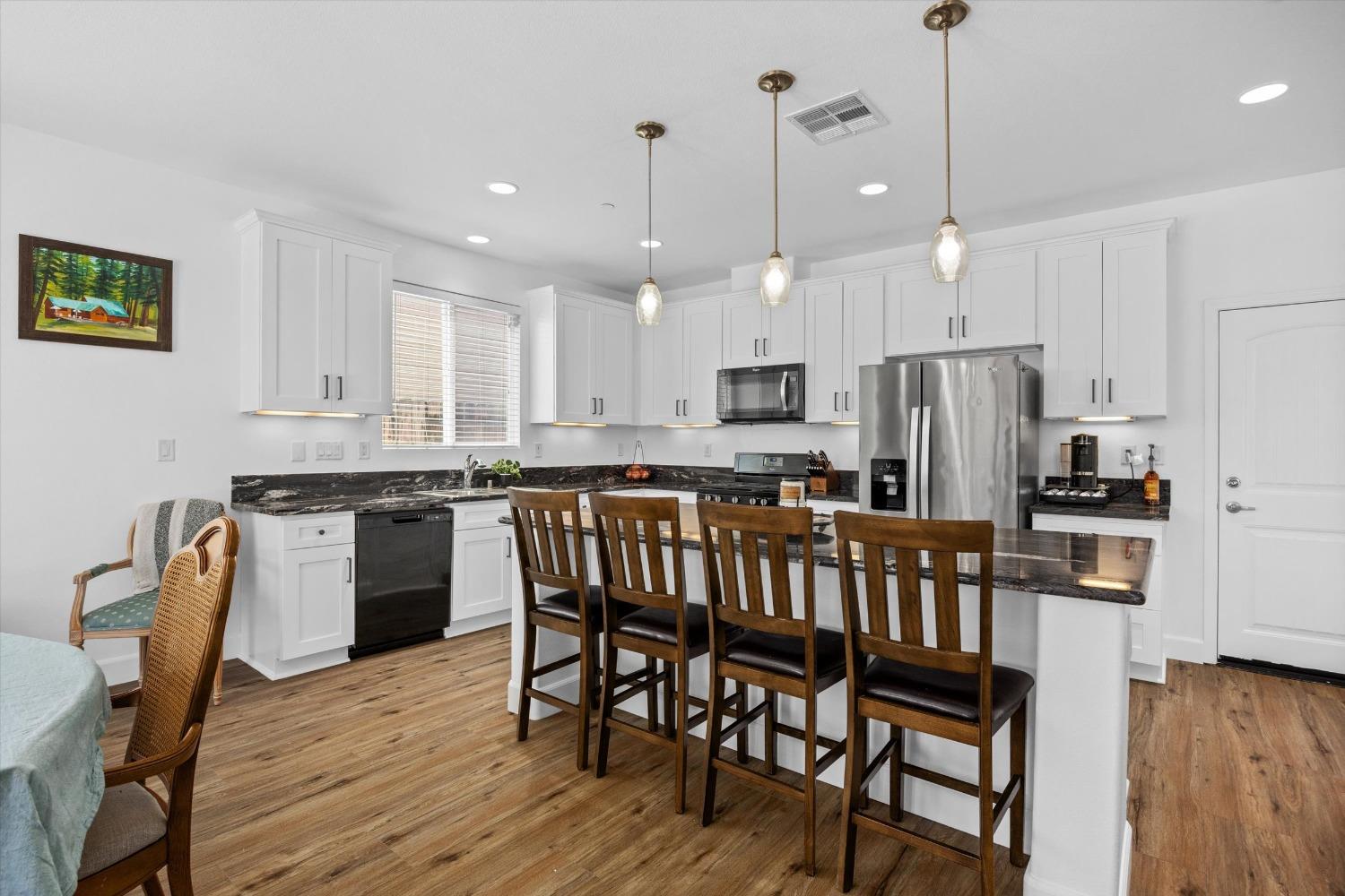5407 Mensen Drive Bakersfield, CA 93313 - Photo 13 of 36 a kitchen with stainless steel appliances granite countertop a dining table chairs refrigerator and sink