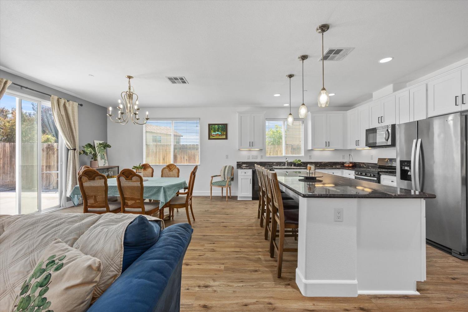 5407 Mensen Drive Bakersfield, CA 93313 - Photo 14 of 36 a kitchen with stainless steel appliances granite countertop a stove a refrigerator a kitchen island a couches and chairs with wooden floor