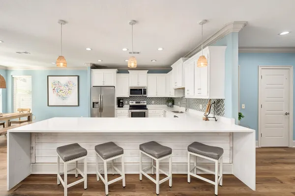 a large kitchen with a large counter top a sink stainless steel appliances and cabinets